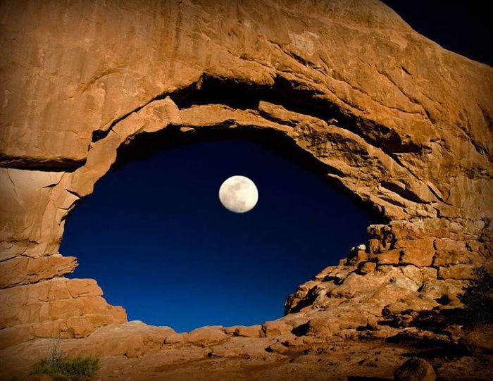Foto de una cueva con la luna apareciendo en un agujero en el medio