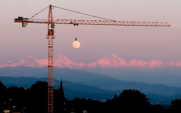 Foto de una grúa sosteniendo la luna al fondo