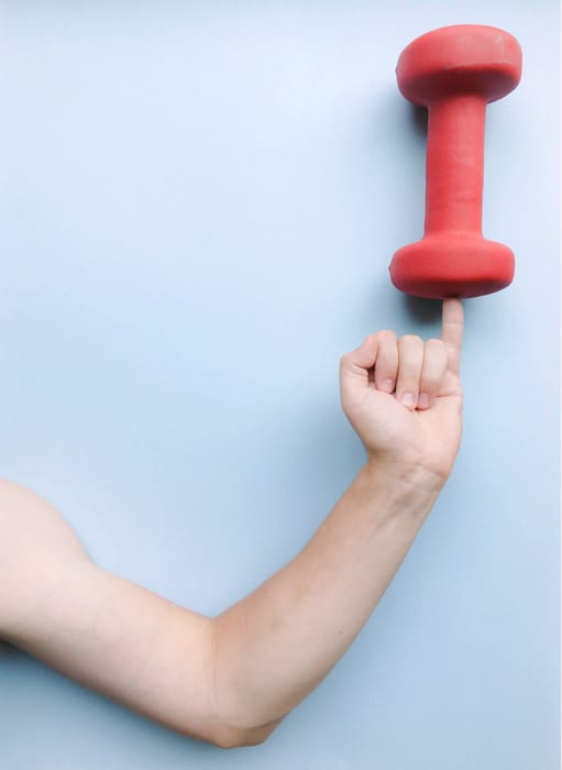 Una imagen de un truco de perspectiva con un brazo sosteniendo un peso sobre el dedo meñique.