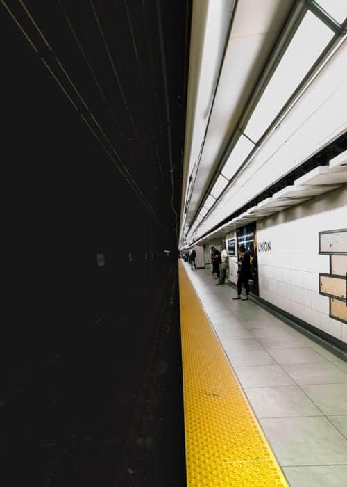 El oscuro túnel del metro en la mitad y la gente esperando en el andén brillante