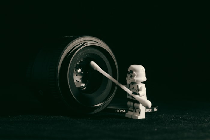 Una figura de lego limpiando la lente de una cámara.