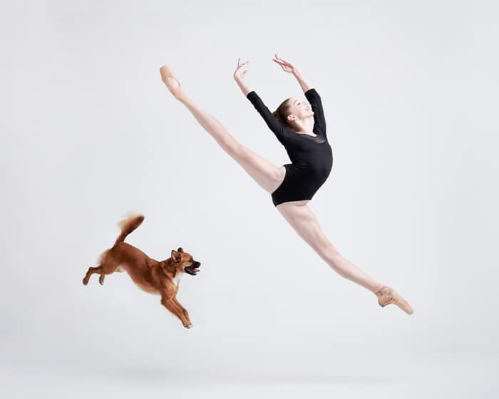 Una bailarina saltando al lado de un perrito.