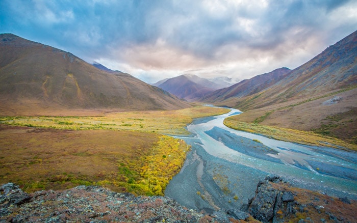 Una impresionante fotografía otoñal de paisajes de montañas y un río.
