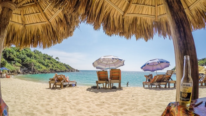 Una bonita escena de playa enmarcada por sombrillas de paja - trabajos de fotografía de viajes