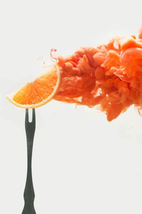una rodaja de naranja en un tenedor: configuración para fotografiar pintura colorida en fotografía acuática