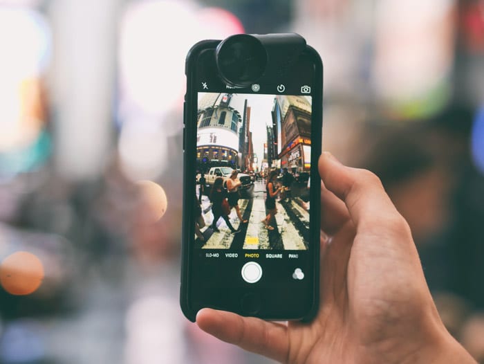 Una mano que sostiene un teléfono inteligente para tomar una foto de una escena callejera concurrida