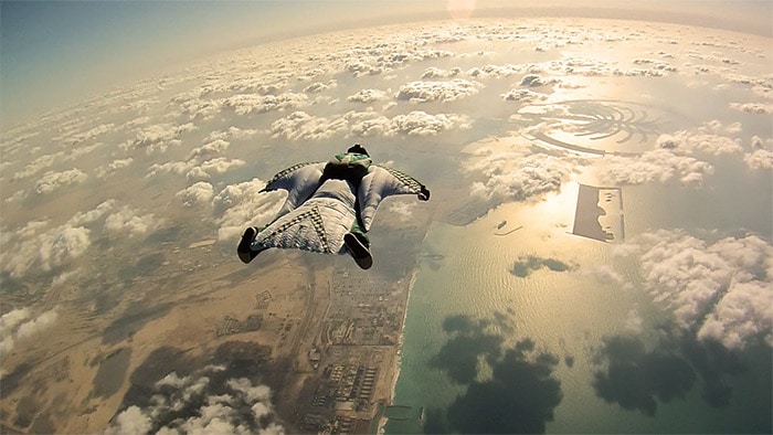 Un hombre volando en un traje de paracaidismo por encima de las nubes.