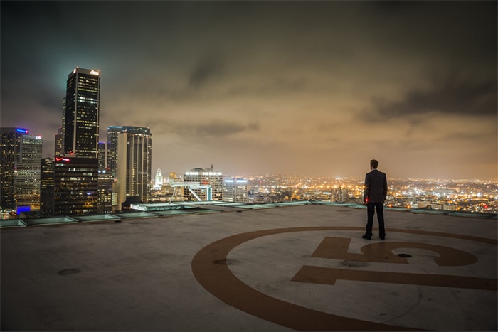 Un hombre de pie en la azotea de un edificio con un horizonte de la ciudad al fondo