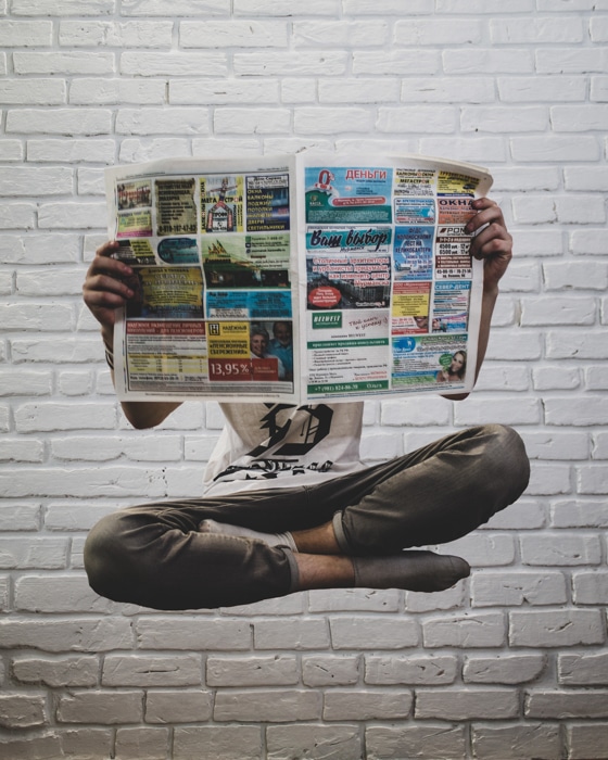 Un hombre levitando y leyendo un periódico para fotografía profesional.