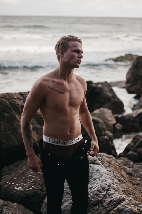 Un modelo masculino posando en topless en una playa