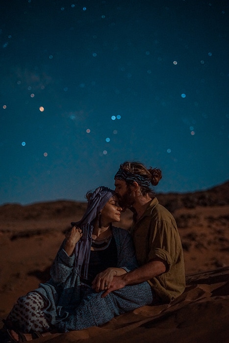 Una pareja sentada afuera bajo las estrellas.