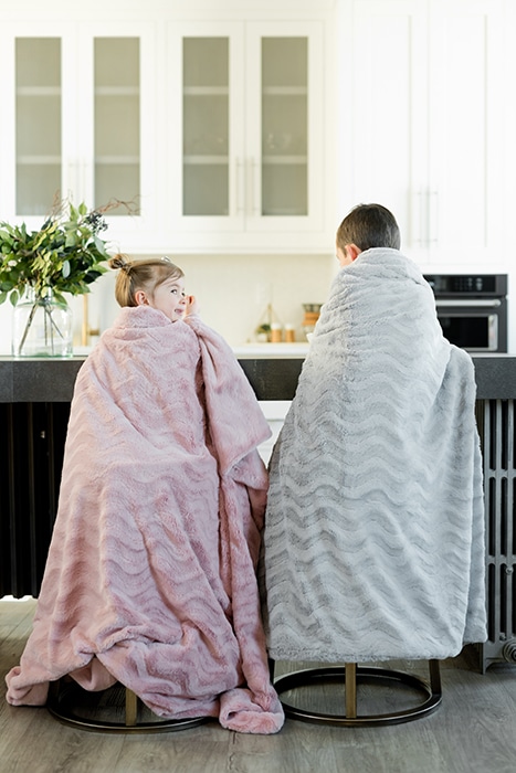 Dos niños pequeños sentados en la cocina envueltos en mantas