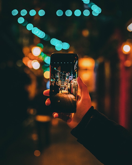 Una persona que toma una foto de una calle de noche con un teléfono inteligente: desafíos de fotografía