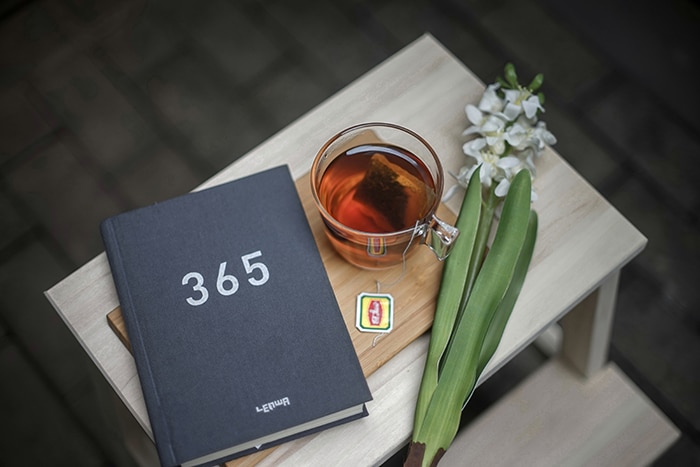 Un bodegón con un libro, una taza de té y una flor sobre una mesa.