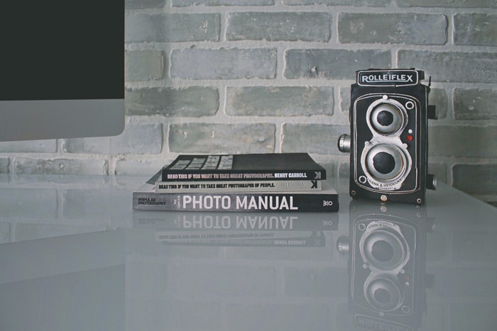 una cámara roliflex y libros de fotografía sobre una mesa - configuración manual de la cámara