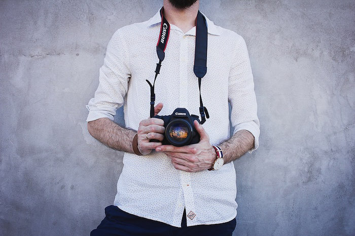 Un fotógrafo sosteniendo una cámara Canon DSLR