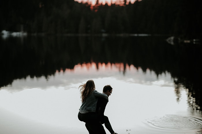 un hombre que le da a una mujer una espalda a cuestas frente a un lago