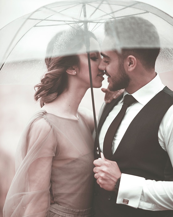 Foto romántica de una pareja joven posando bajo un paraguas