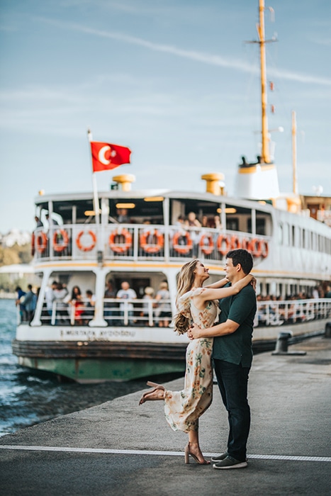 Una pareja abrazándose en un muelle frente a un barco grande