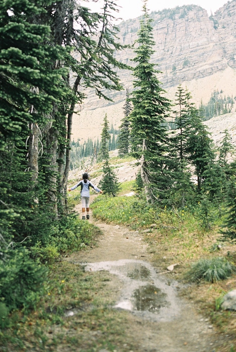 Foto de una niña dando un paseo por un bosque y un paisaje montañoso luciosos