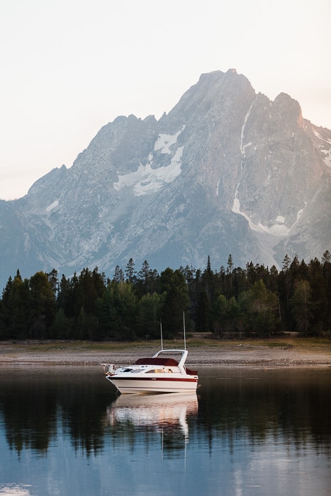 Una imagen serena de un barco en un lago con una montaña detrás