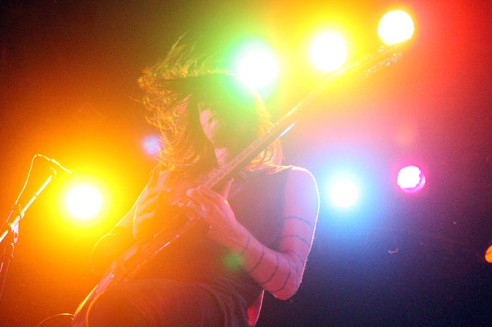 Colorida fotografía de concierto de un guitarrista desde un ángulo bajo.