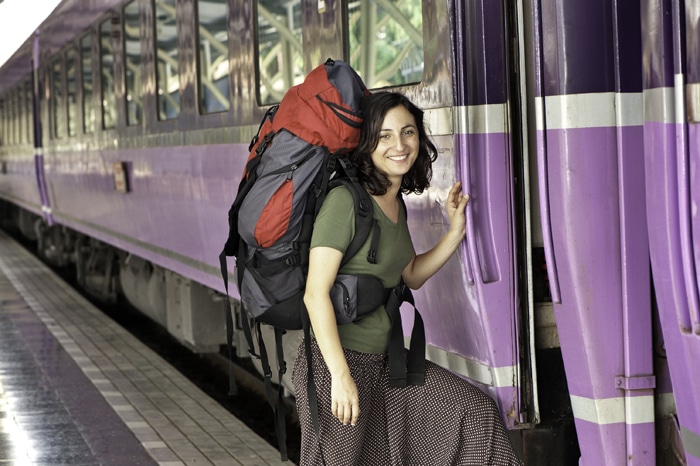 Foto de un mochilero de pie junto a un tren.
