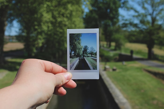 Una mano que sostiene una foto polaroid de un paisaje dentro de un paisaje