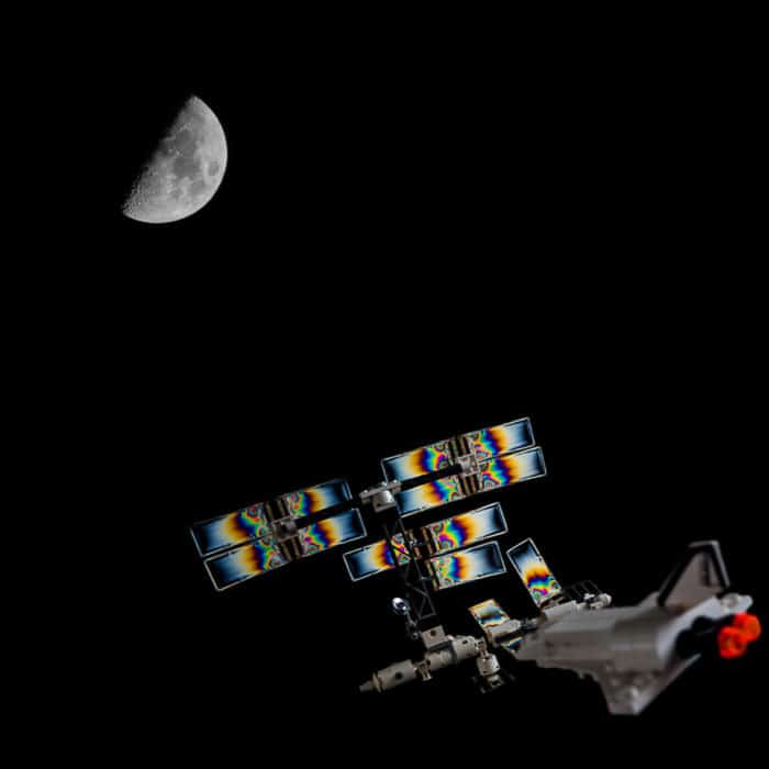 Una imagen compuesta de una estación espacial LEGO fotoelástica y la Luna
