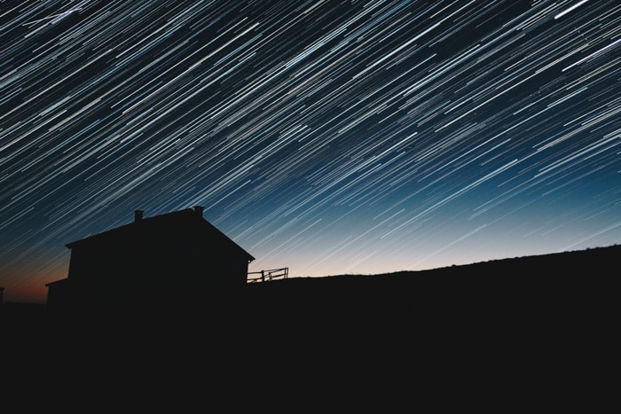 Un impresionante cielo lleno de estrellas sobre la silueta de una casa.