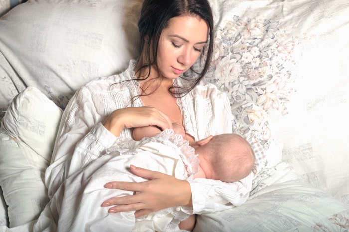 Idea de la foto del recién nacido de la madre alimentando al bebé en la cama