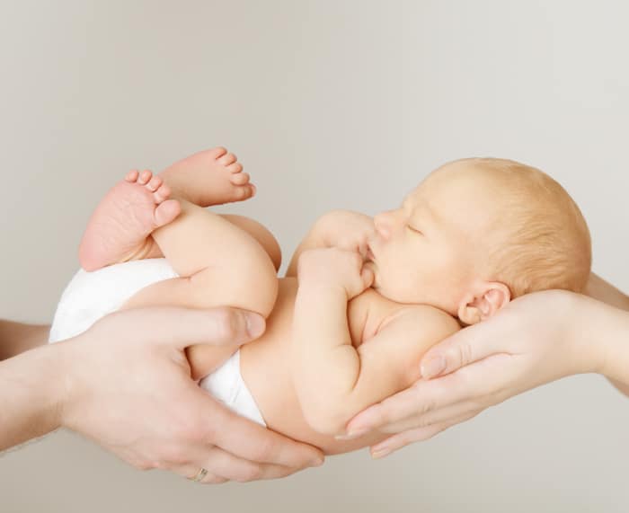 Dulce idea de la foto del recién nacido del bebé descansando sobre las manos de los padres