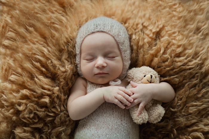 Dulce retrato de un bebé recién nacido sosteniendo un oso de peluche