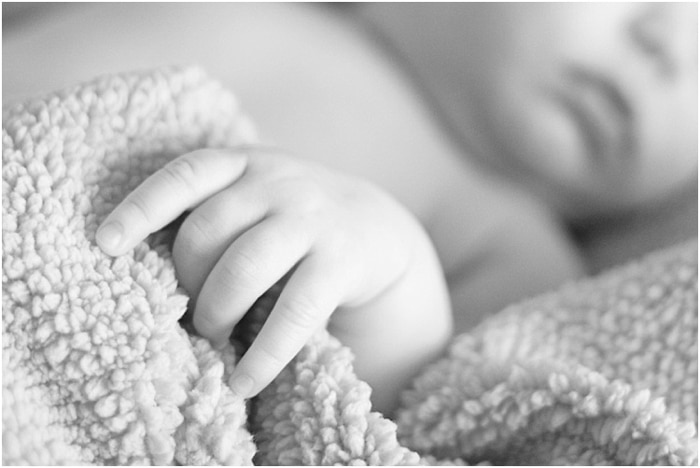 Cerrar fotografía en blanco y negro de la mano del bebé agarrando una manta durante una sesión de retrato de recién nacido