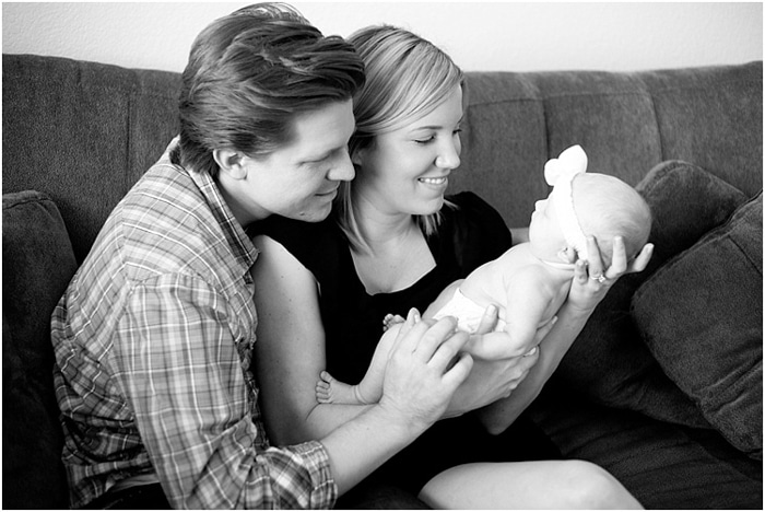 Fotografía en blanco y negro de un padre sentado en un sofá sosteniendo recién nacido