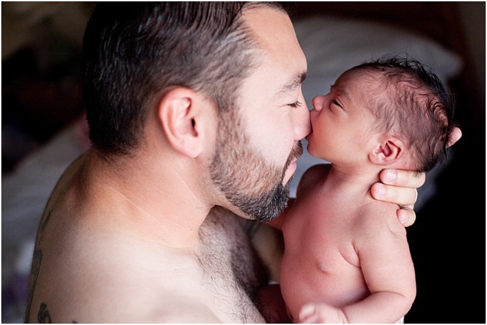 Cerrar padre acariciando al bebé, bebé mordiendo la nariz del padre durante una sesión de fotos del recién nacido