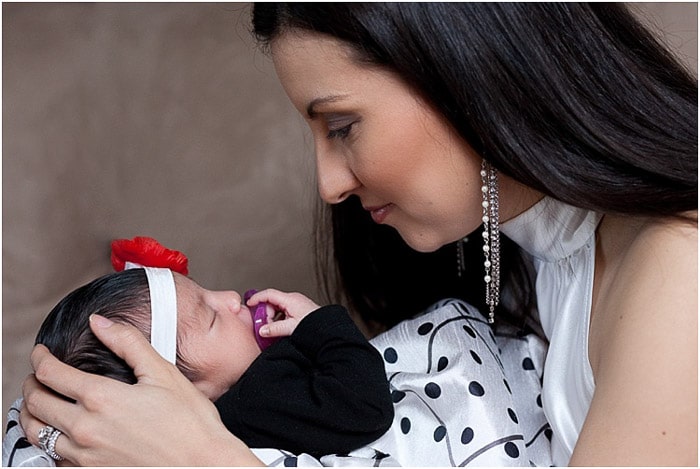 Una madre posando con su bebé recién nacido para una sesión en una empresa de fotografía de recién nacidos