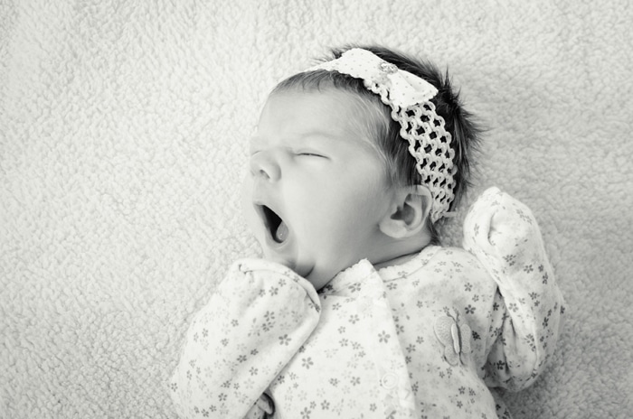 Fotografía en blanco y negro de un bebé recién nacido con un lindo traje de mameluco