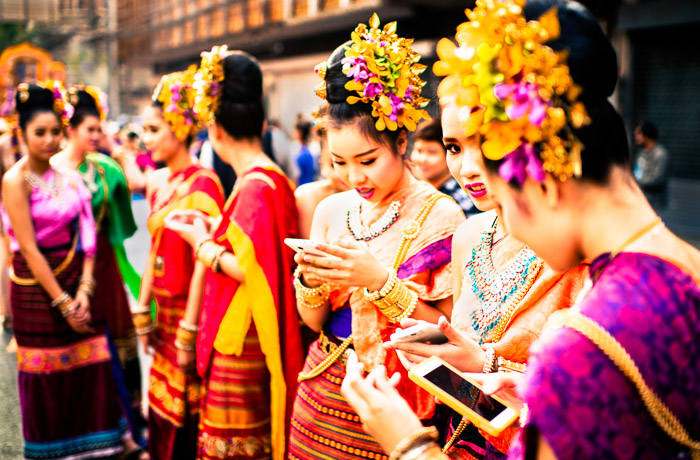 Un retrato callejero de niñas revisando sus teléfonos inteligentes antes del inicio del desfile anual de flores en Chiang Mai, Tailandia.  Fotos que cuentan una historia