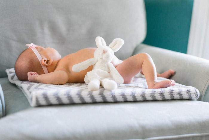 Un bebé recién nacido posado sobre una alfombra de oso de peluche 