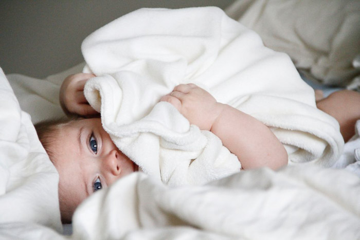 Un bebé recién nacido posado en una manta blanca.