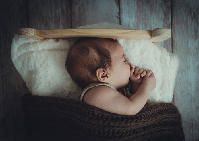Un retrato de un recién nacido en una cama pequeña. 