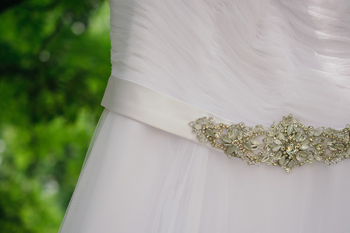 Un primer plano de los detalles de un vestido de novia en una sesión fotográfica de bodas al aire libre 