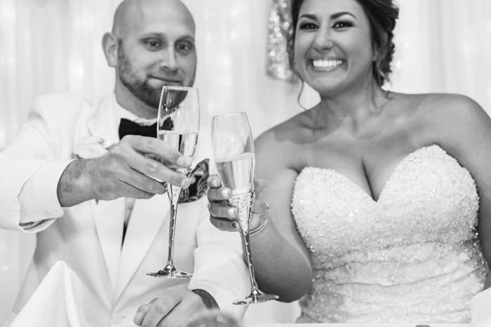 Un retrato en blanco y negro de una novia y un novio brindando en la recepción de su boda