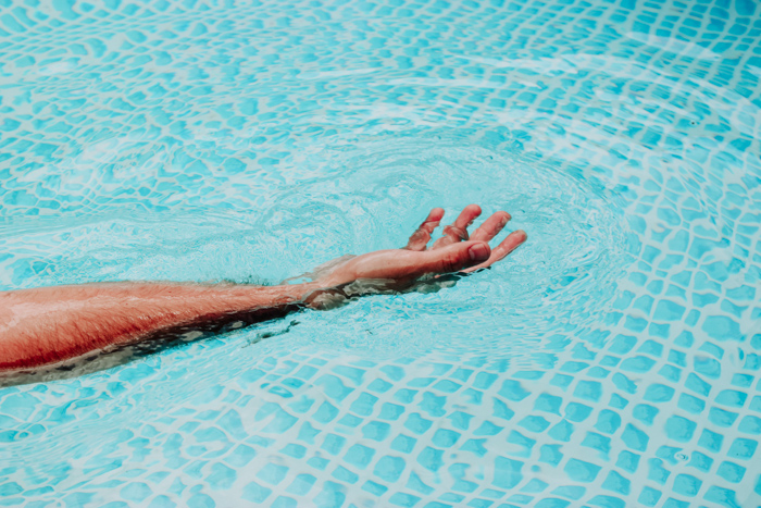 La mano de una persona se extiende en el agua usando un esquema de color naranja y azul