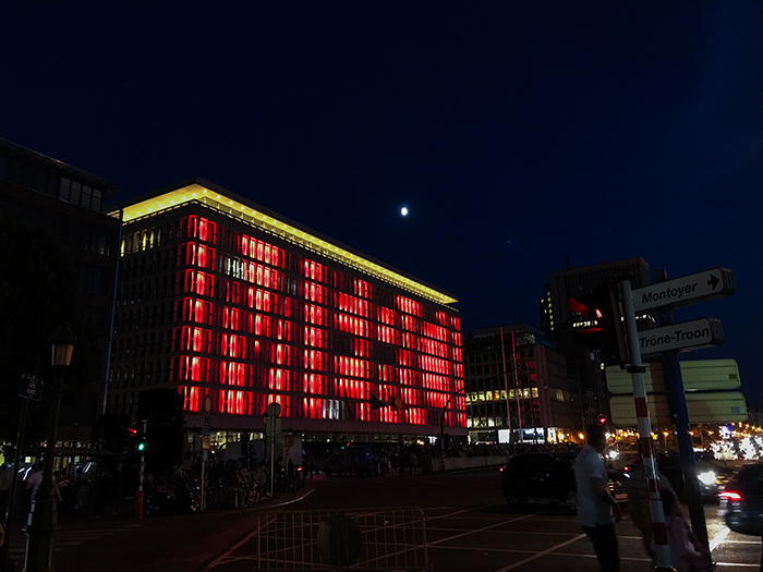 Foto de un edificio rectangular con muchas ventanas por la noche, con luces cambiantes en el frente