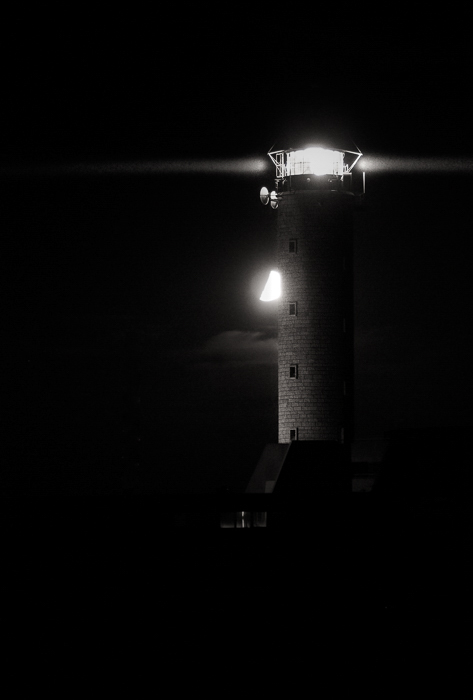foto en blanco y negro de la luna detrás del faro en Cap-Gris-Nez contra un cielo nocturno negro
