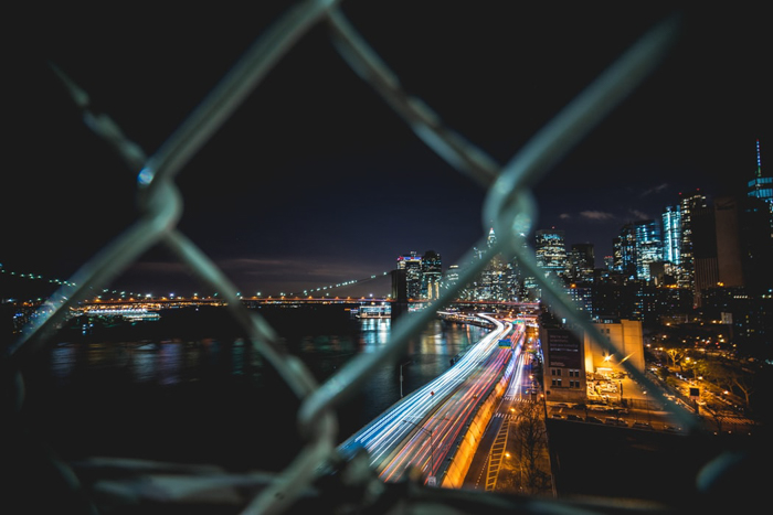 Una fotografía nocturna de un paisaje urbano a través de una valla de cadena
