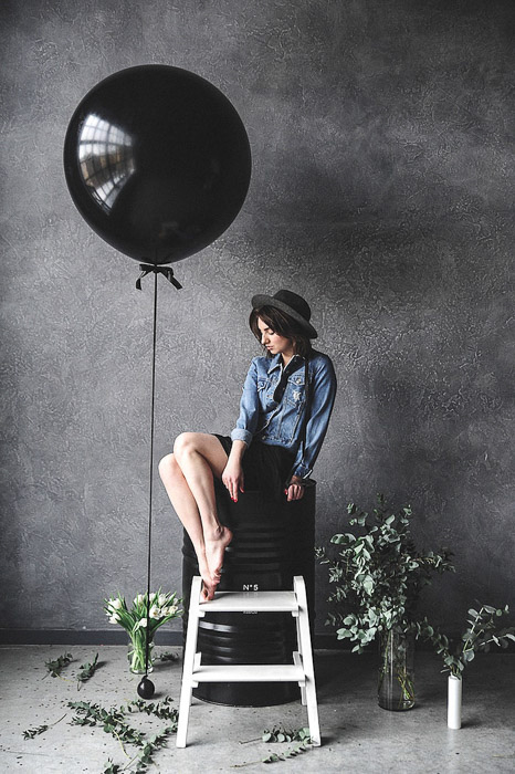 retrato de una elegante modelo femenina sentada junto a un globo negro