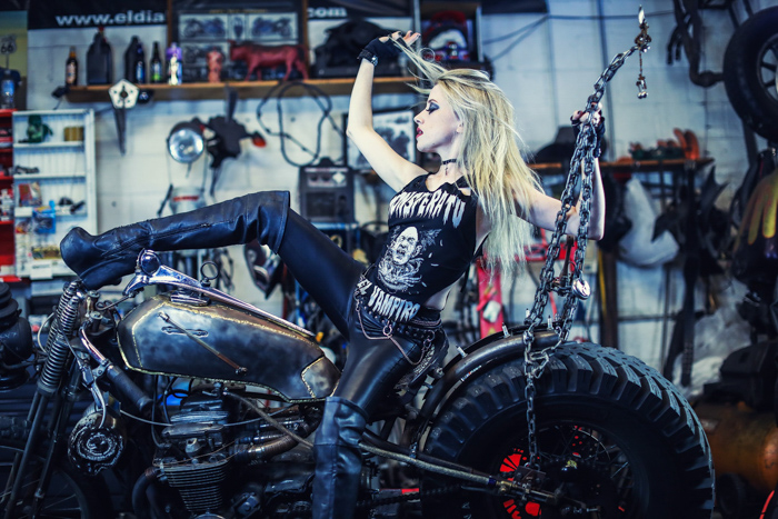 una chica con equipo de motociclista posando en una moto